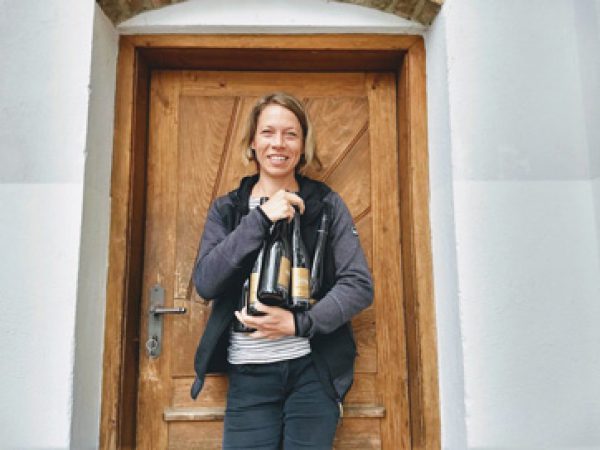 Silke Mayr vor einer Tür mit vielen Flaschen im Arm